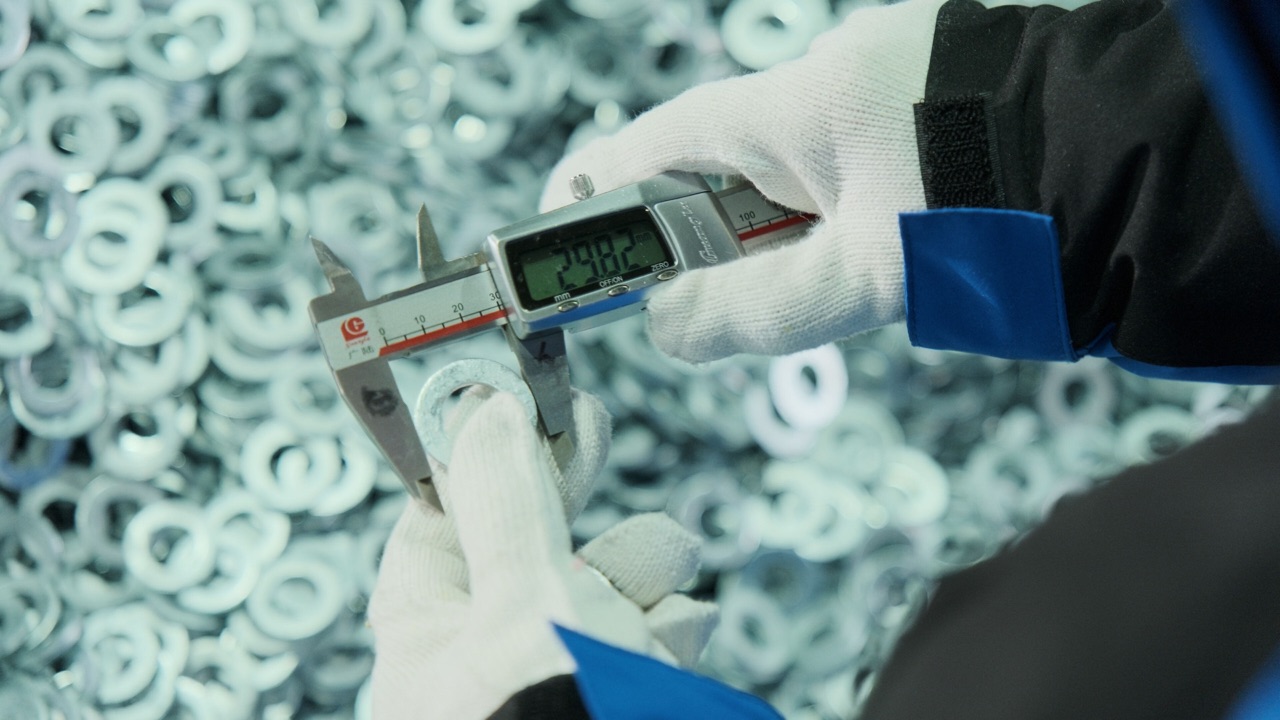 Inspector measuring a washer with a digital caliper